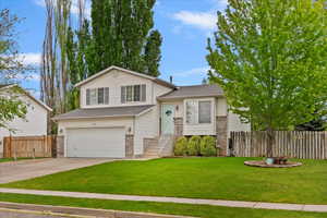 Tri-level home with fence, a garage, a front lawn, and concrete driveway