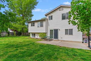 Back of house featuring a lawn, a patio area, and fence