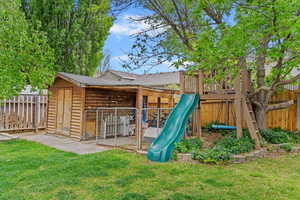 View of playground with a fenced backyard, a yard, and an outbuilding