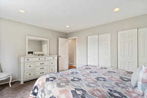 Bedroom featuring dark carpet, multiple closets, recessed lighting, and visible vents