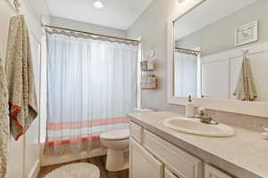 Bathroom featuring toilet, wood finished floors, shower / bath combo, vanity, and recessed lighting
