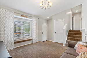 Living area with carpet, stairway, baseboards, and a notable chandelier
