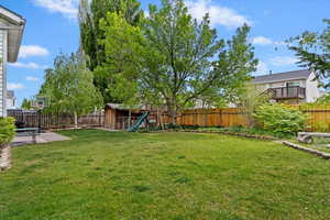View of yard featuring an outbuilding, a patio, a fenced backyard, and a storage unit