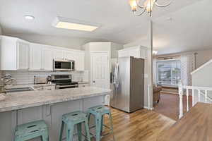 Kitchen with light countertops, stainless steel appliances, a sink, and vaulted ceiling