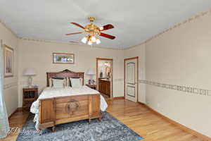 Primary Bedroom featuring visible vents, baseboards, a ceiling fan, light wood finished floors, and ensuite bath