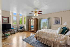 Primary Bedroom with a textured ceiling, ceiling fan, and wood finished floors