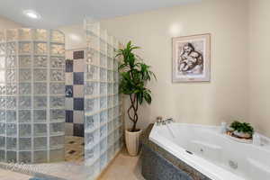 Primary bathroom featuring a jetted tub, a walk in shower, and tile patterned floors