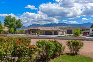 View of front of property with fence, a tile roof, a garage, a mountain view, and concrete driveway