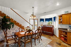 Dining area with a textured ceiling, a chandelier, baseboards, visible vents, and stairway