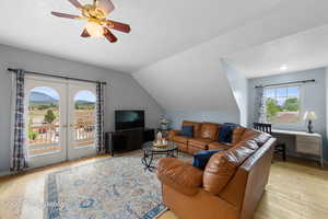 Apartment Living area with light wood-style floors, a textured ceiling, french doors, a ceiling fan, and vaulted ceiling