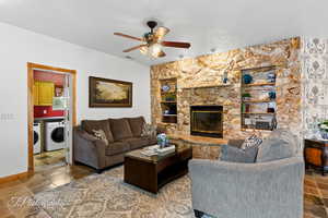 Living area with separate washer and dryer, a ceiling fan, baseboards, and a fireplace