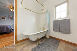 Bathroom featuring crown molding, ceiling fan, a freestanding bath, baseboards, and ensuite bathroom