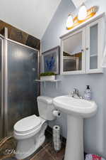 Apartment Full bathroom with a sink, toilet, tile patterned floors, lofted ceiling, and a stall shower