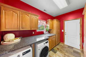 Laundry room with visible vents, stone finish flooring, cabinet space, and washing machine and clothes dryer