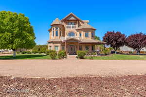 Victorian-style house featuring a front lawn, a porch, a tile roof, and stone siding