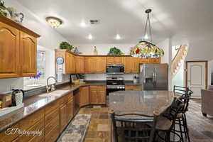 Kitchen with stone tile flooring, brown cabinetry, visible vents, a sink, and appliances with stainless steel finishes