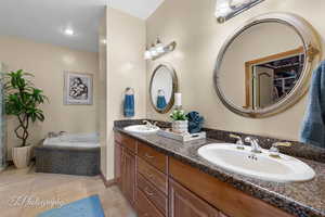 Primary bathroom featuring double vanity, a sink, a bath, and tile patterned floors
