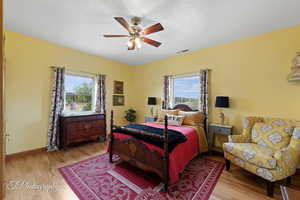 Bedroom with visible vents, a ceiling fan, baseboards, and wood finished floors