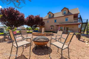 Back of house with stairs, a fire pit, stucco siding, and a patio area