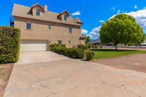 View of property exterior with an attached garage, a tile roof, stucco siding, a chimney, and concrete driveway