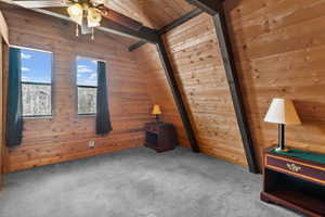 Lofted ceiling with beams, a ceiling fan,  and carpet flooring