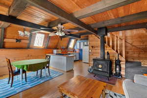 Great room featuring a wood stove, wood  flooring, beamed ceiling