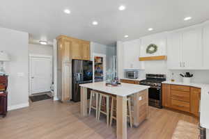 Kitchen with a kitchen island, light countertops, light wood-style floors, a breakfast bar, and stainless steel appliances