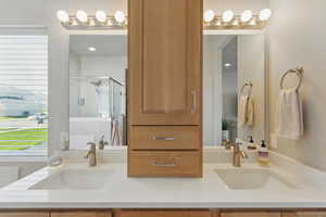 Bathroom with double vanity, a sink, and a stall shower