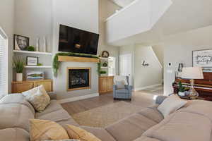 Living room featuring baseboards, a glass covered fireplace, light wood finished floors, and a towering ceiling