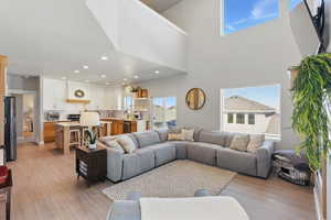 Living room with recessed lighting, light wood-style flooring, and a towering ceiling