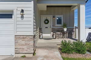 Entrance to property with board and batten siding, covered porch, and stone siding