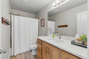 Bathroom featuring vanity, visible vents, wood finished floors, toilet, and shower / bath combo
