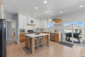 Kitchen featuring light wood-style floors, a breakfast bar area, light countertops, a sink, and stainless steel appliances