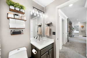 Bathroom featuring vanity, ornamental molding, baseboards, and toilet