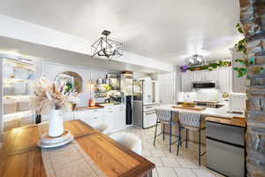 Kitchen with white cabinets, stainless steel appliances, an inviting chandelier, and tasteful backsplash