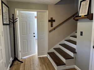 Foyer featuring baseboards, stairs, and wood finished floors