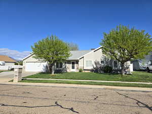 View of front of home with a garage, stucco siding, driveway, and a front lawn