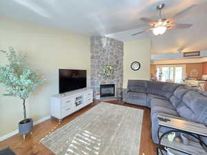 Living area with baseboards, a ceiling fan, wood finished floors, and a fireplace