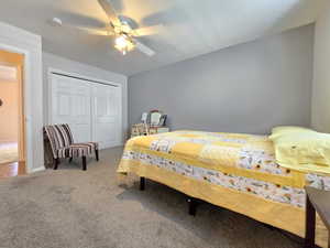 Carpeted bedroom featuring a ceiling fan and a closet