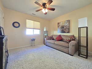 Carpeted living area featuring baseboards, ceiling fan, and visible vents