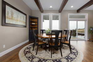 Dining area with dark hardwood / wood-style floors and beam ceiling