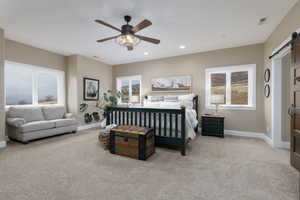 Carpeted bedroom with a barn door and ceiling fan