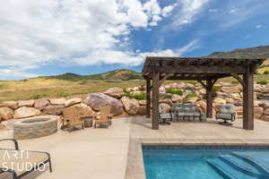 View of swimming pool with a mountain view, a pergola, a patio area, and an outdoor fire pit