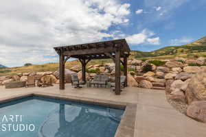 View of swimming pool with a mountain view, a patio area, and a pergola