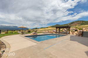 View of swimming pool with a mountain view, a pergola, and a patio area