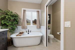 Bathroom with tile patterned flooring, a bath, and toilet