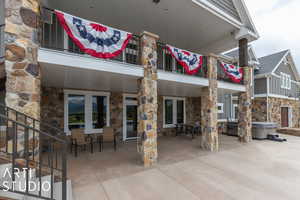 Back of house with a balcony, a hot tub, and a patio area