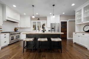 Kitchen featuring decorative light fixtures, high quality appliances, white cabinets, a kitchen bar, and a center island