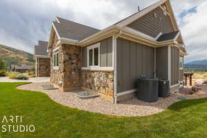 View of home's exterior featuring cooling unit, a mountain view, and a lawn