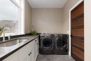 Washroom featuring sink, cabinets, light tile patterned floors, a mountain view, and washer and clothes dryer